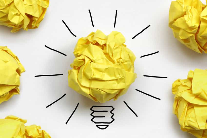 Yellow scrunched up paper of discarded content writing idea surrounded by lightbulb drawing.