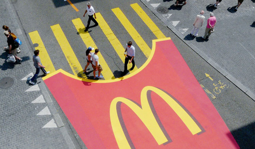 McDonald's fries box painted on the street. The fries are serving as a zebra crossing.