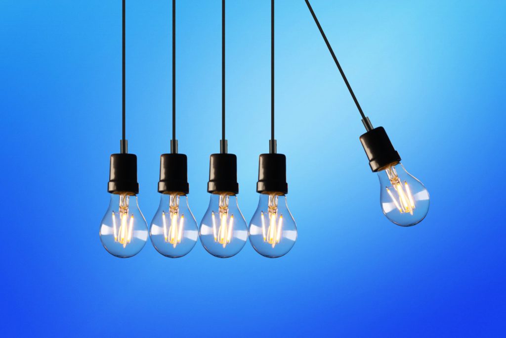 5 hanging lightbulbs on blue background, with one pulled at an angle. 